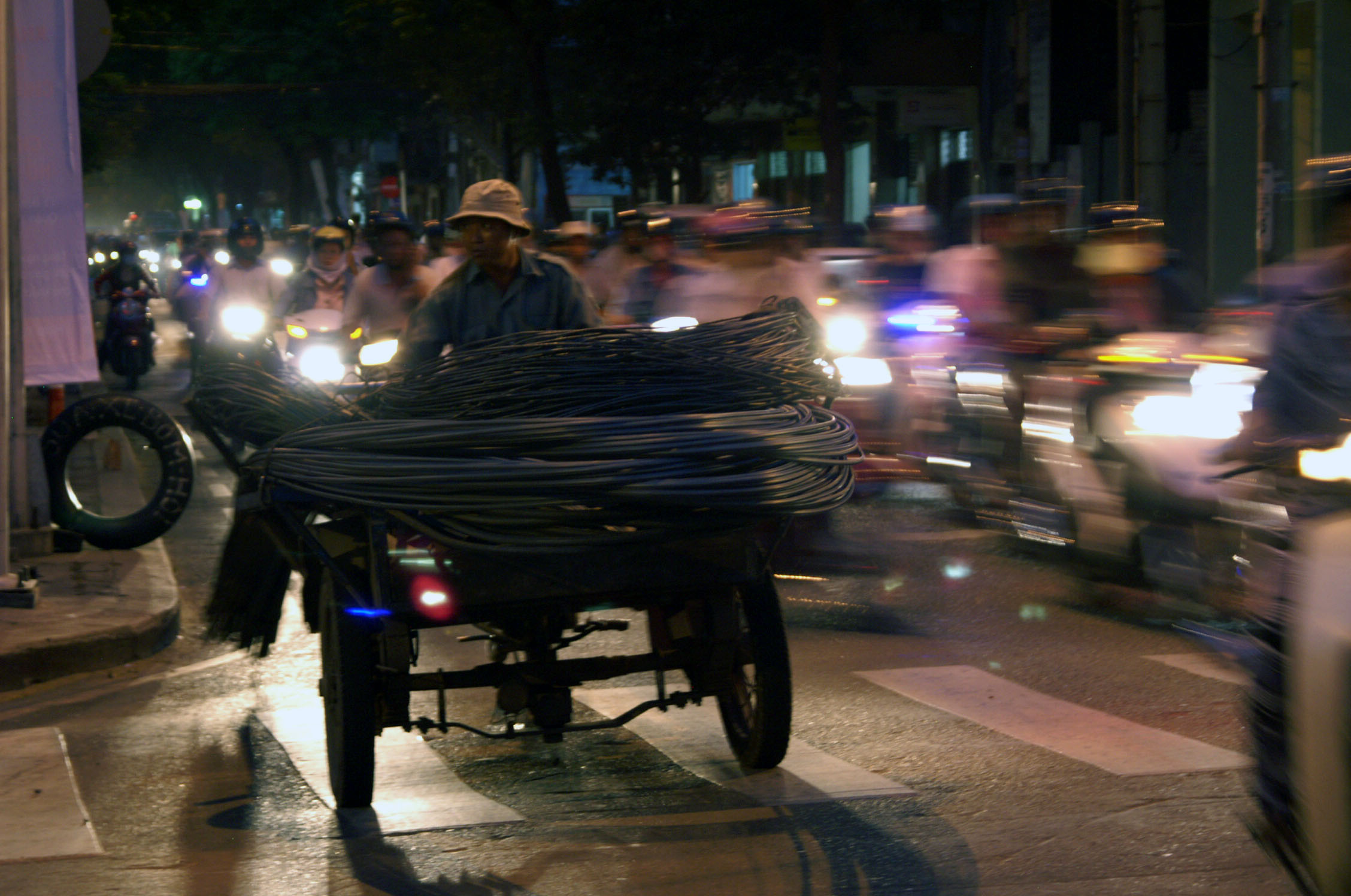 Rikshaw driver in Ho Chi Minh City (Saigon) transporting iron cable at dusk light conditions