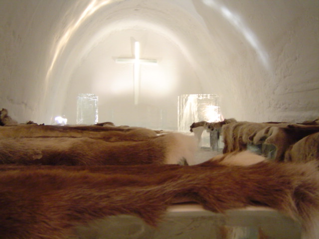 Illuminated church at the Ice Hotel with reindeer fur seating