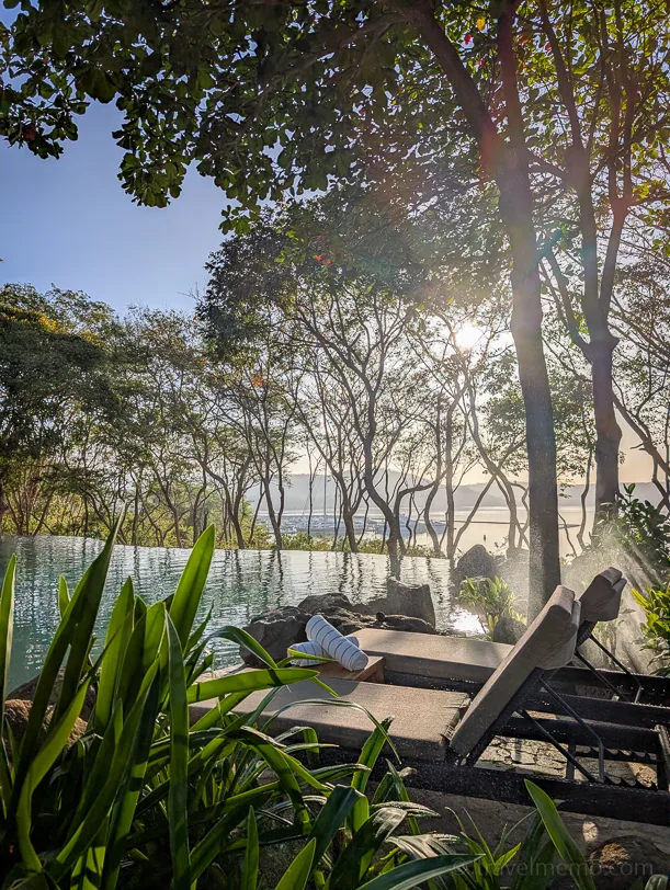 Infinity pool at the Andaz Peninsula Papagayo surrounded by tropical trees with a view of the Pacific, sunrise in the background