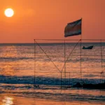 The golden hour bathes the Pacific beach with Costa Rica flag in warm light