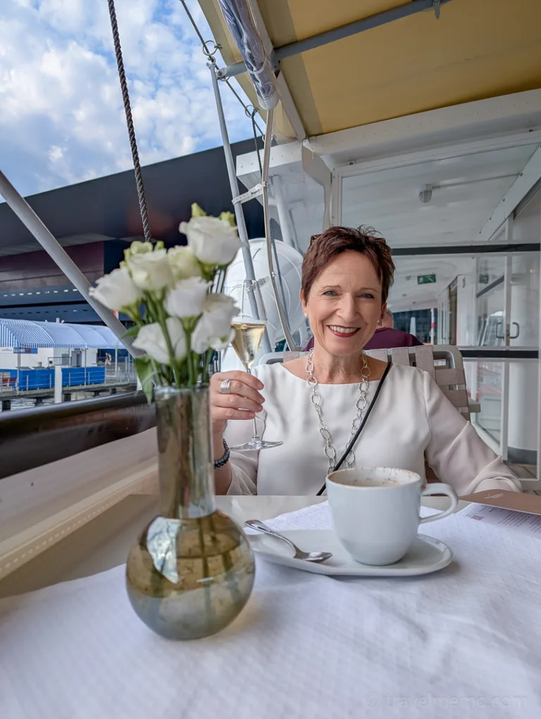 A woman is sitting at a set table with coffee and flowers on a steamboat on Lake Lucerne near Lucerne