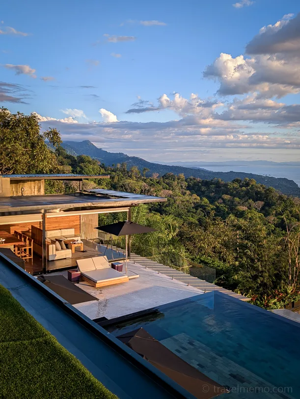 Kura Boutique Hotel with large pool and panoramic view over green mountain landscape and rainforest in Costa Rica at sunset.