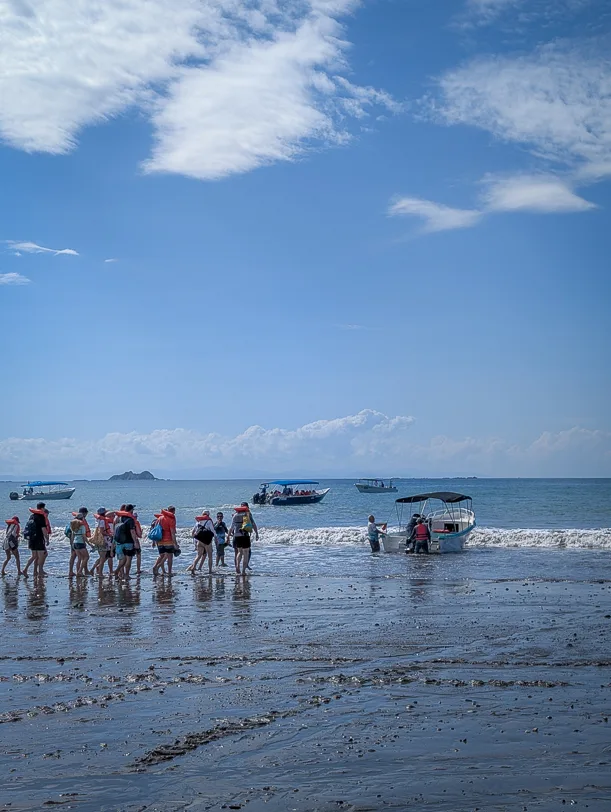Tourists board a boat at low tide on Uvita beach for a whale watching tour in the Marino Ballena National Park