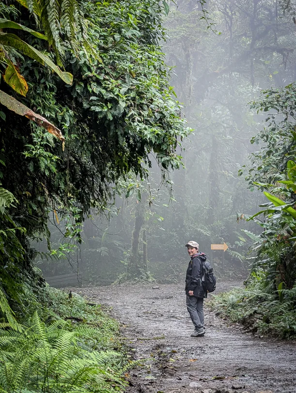 Travel blogger Katja with backpack on a path through the misty Monteverde cloud forest with lush tropical vegetation