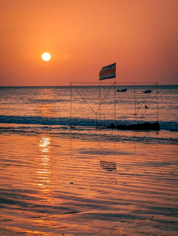 Sunset on the beach with a fishing boat in the foreground, golden light reflected in the wet sand and the waves of the Pacific Ocean